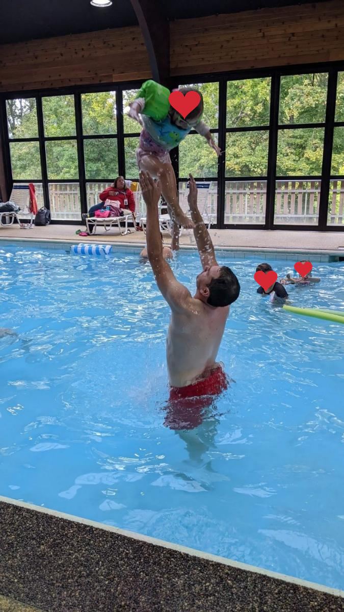 A dad tossing his daughter in the indoor pool